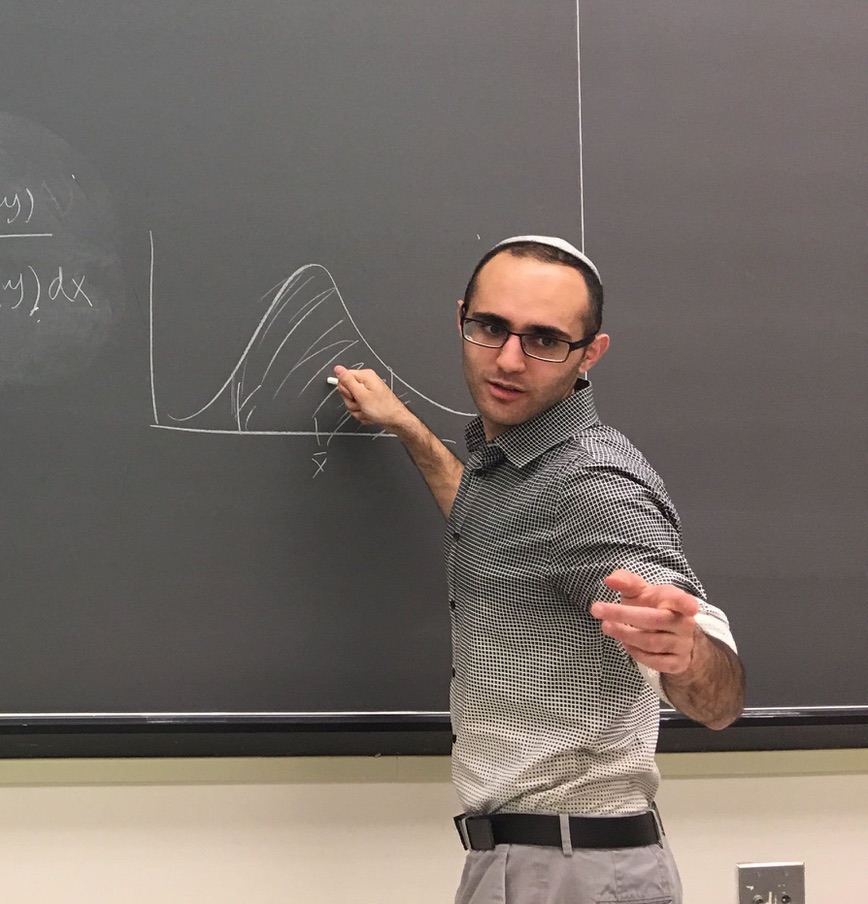 Matthew Sedaghatfar teaching in front of a chalkboard
